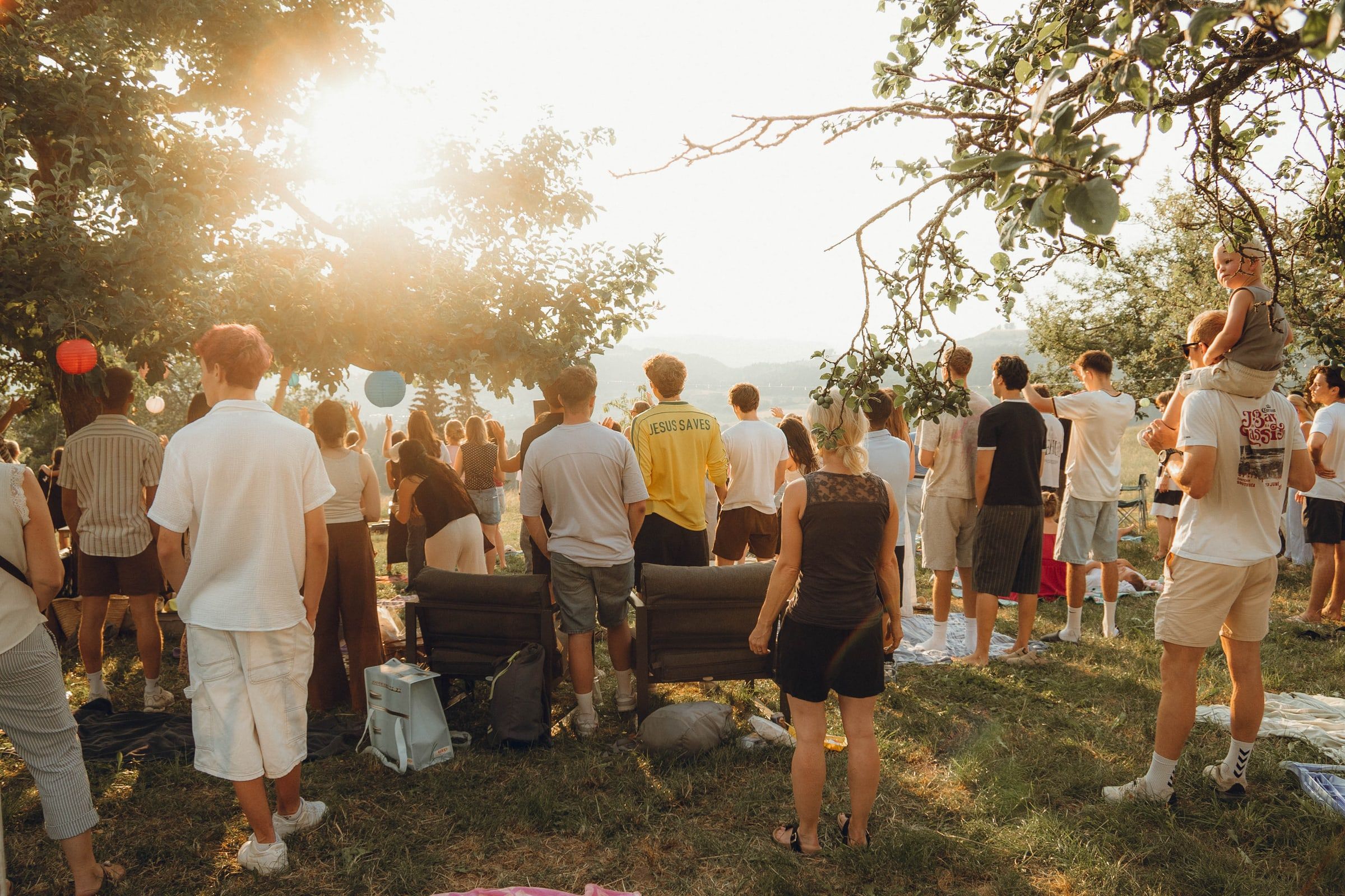 Menschen stehen im Gegenlicht der Abendsonne vor der Bühne