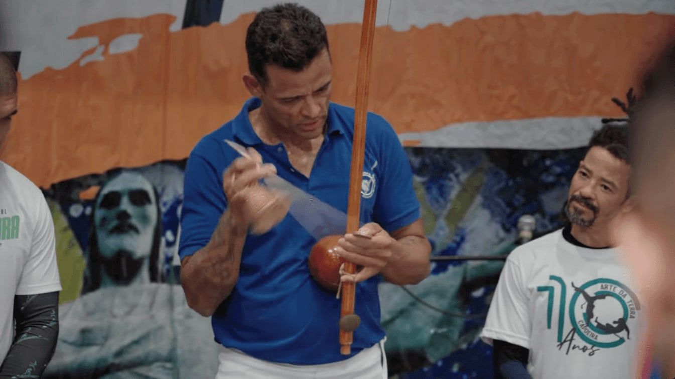 Capoeira-Lehrer spielt den Berimbau vor einem Wandbild